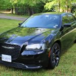 Black Chrysler Sedan Parked on a Grassy Lawn with Trees in the Background; Virginia License Plate Belman 8. Black Chrysler Sedan Parked on a Grassy Lawn with Trees in the Background; Virginia License Plate Belman 8.