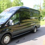 Black Cargo Van Parked on a Suburban Street with Trees Reflected in Its Shiny Surface. Black Cargo Van Parked on a Suburban Street with Trees Reflected in Its Shiny Surface.