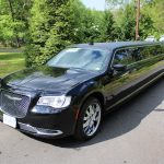 Side View of a Black Stretch Limousine/suv Parked on a Tree-lined Street with Green Foliage in the Background. Side View of a Black Stretch Limousine/suv Parked on a Tree-lined Street with Green Foliage in the Background.
